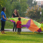 children playing with a parachute in big backyard garden